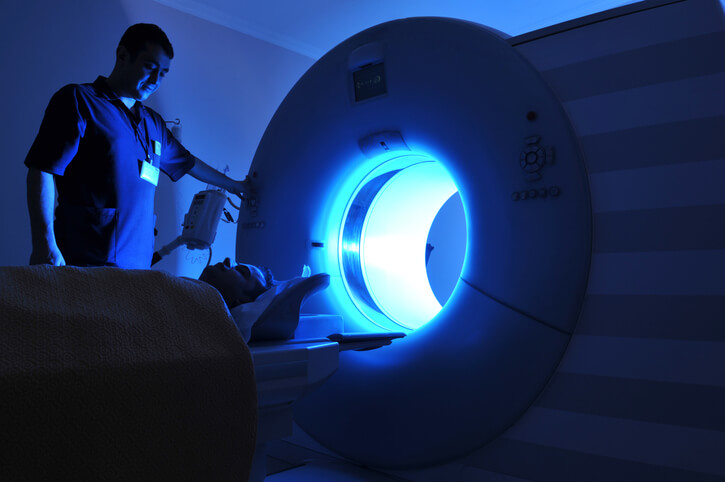 patient entering mri machine in dark room with aid of technician