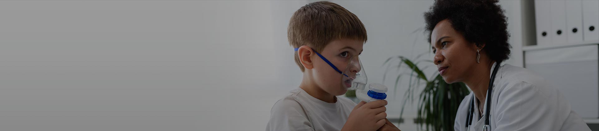 Respiratory therapist giving young boy breathing treatment