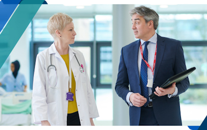 Two healthcare executives conversing in a facility hallway Two healthcare executives conversing in a facility hallway