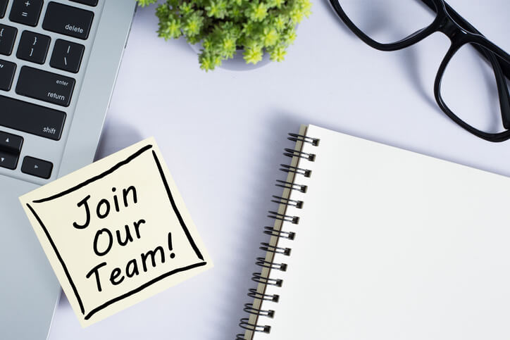Join Our Team sticky note with notepad, laptop and glasses near Join Our Team sticky note with notepad, laptop and glasses near