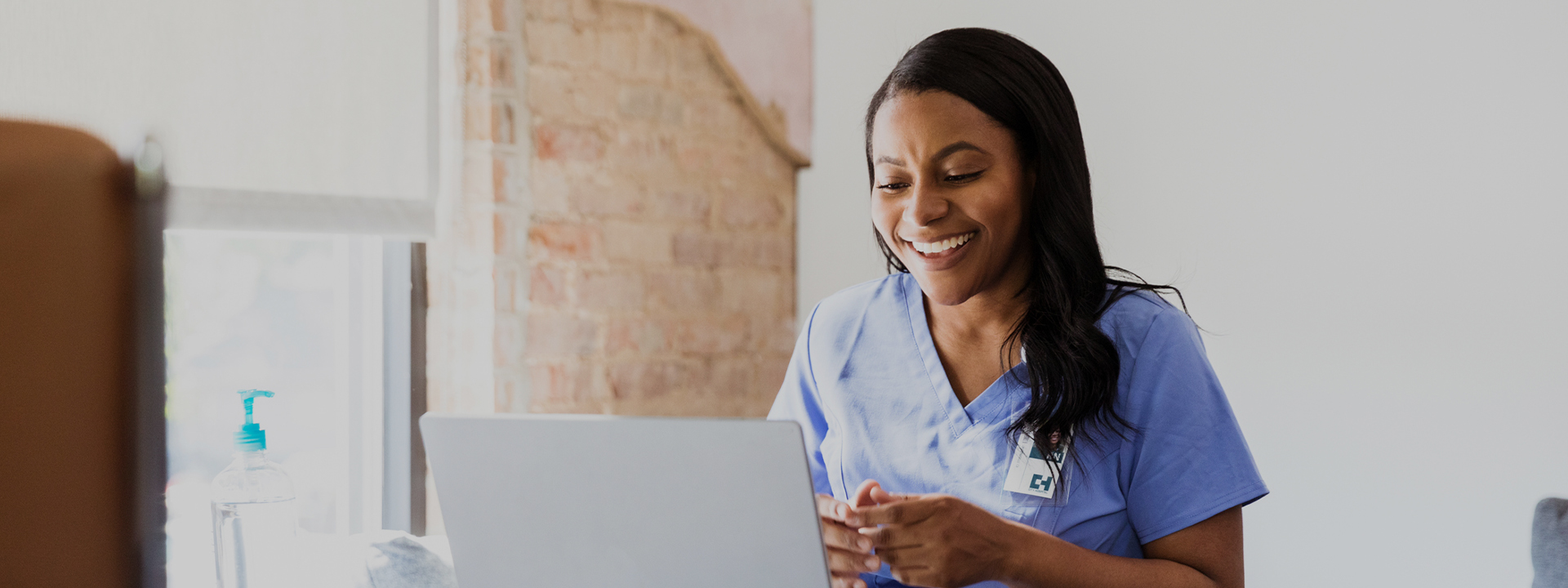 Female healthcare professional smiling while looking at laptop screen