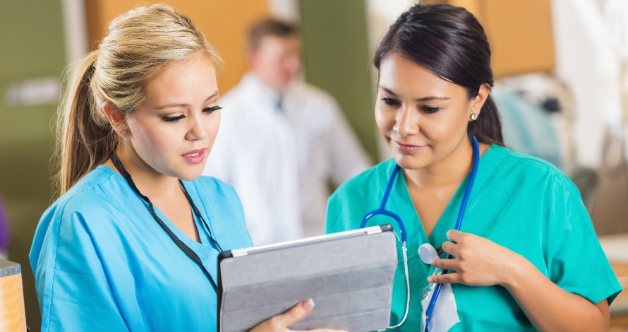 Two nurses looking at info on a tablet computer