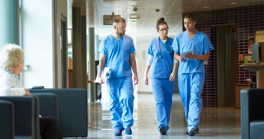 two male nurses and a female nurse walking down a hall