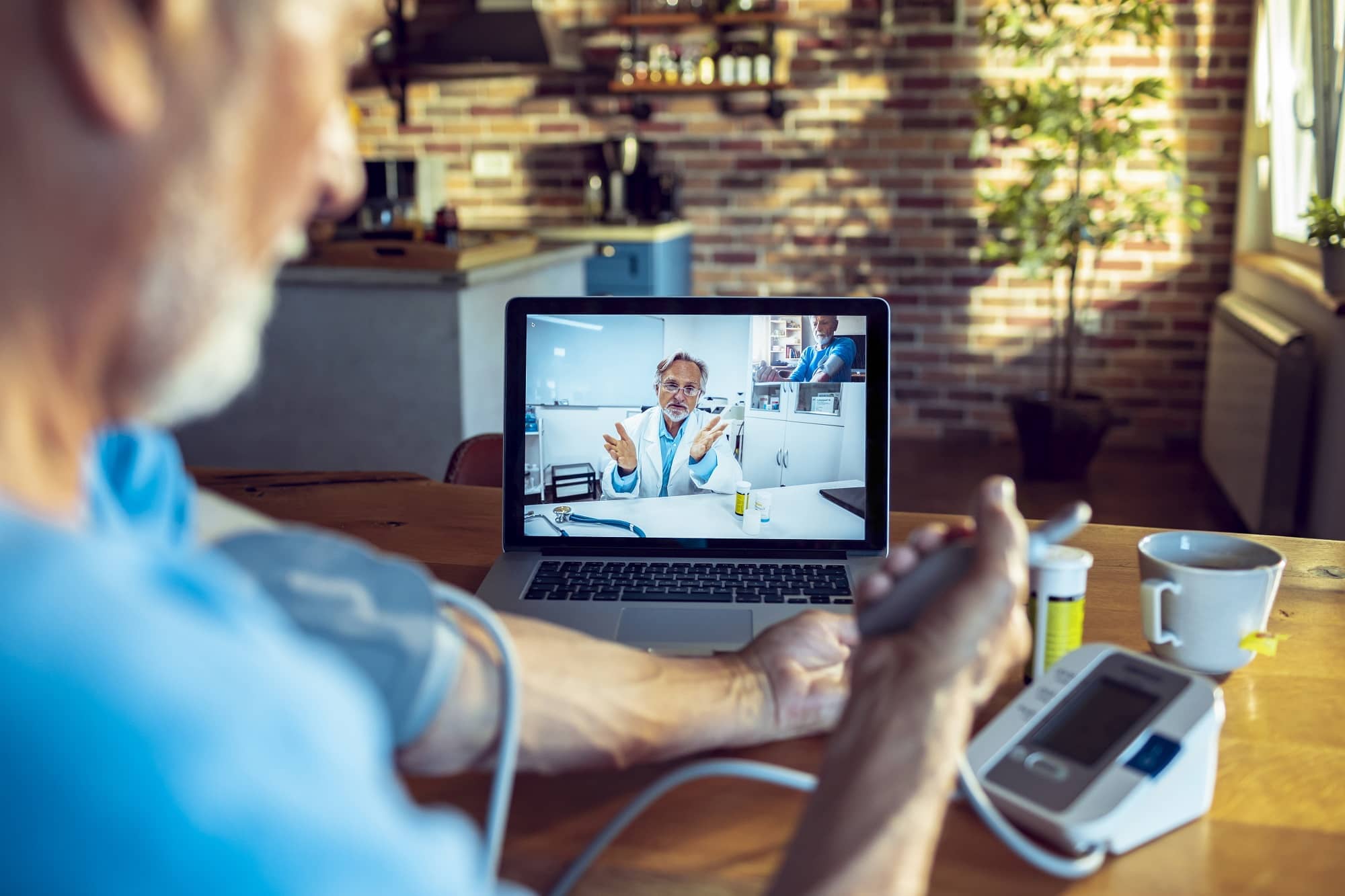 telehealth appointment with doctor visible on computer and patient at home using blood pressure cuff