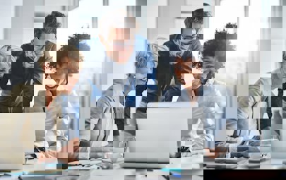 Healthcare executives gathered around a laptop doing work Healthcare executives gathered around a laptop doing work