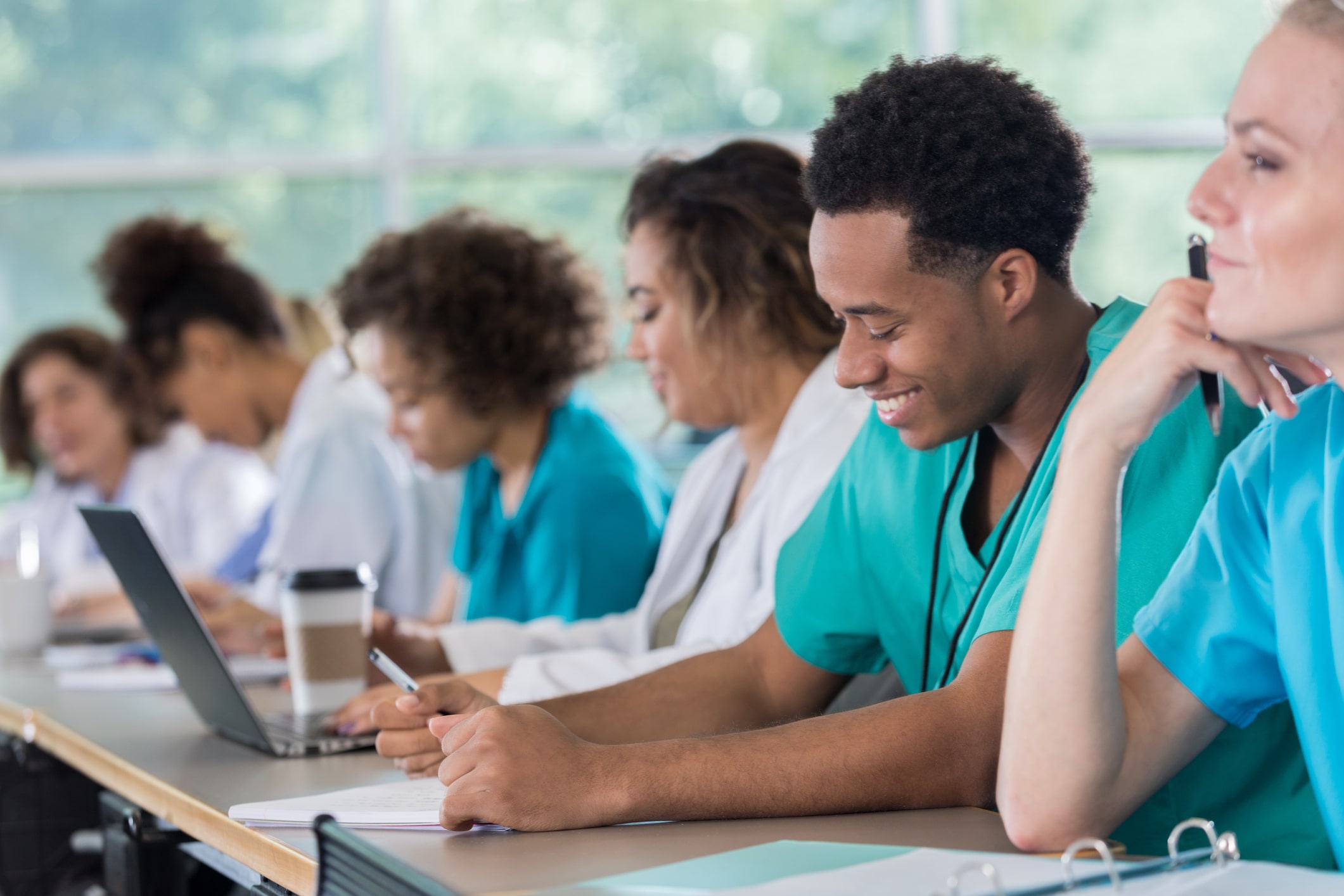 diverse group of med students in green and blue scrubs, happy and engaged 