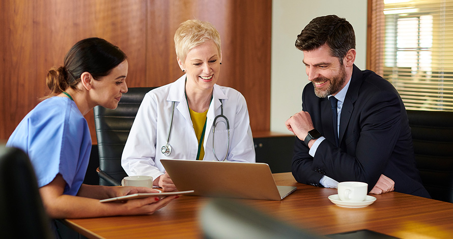 Three medical professionals reviewing information on a laptop