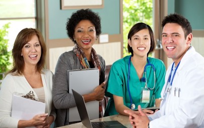 two administrators, one nurse, and one physician next to each other smiling two administrators, one nurse, and one physician next to each other smiling
