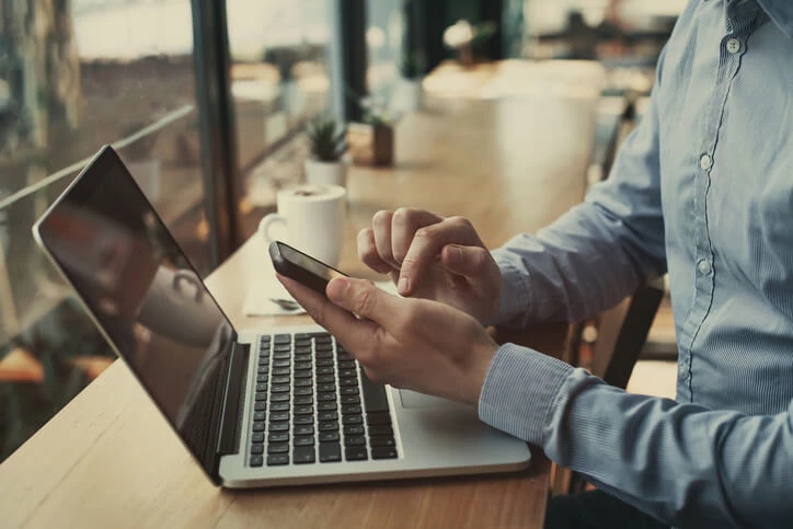 Man with laptop and smart phone in coffee shop