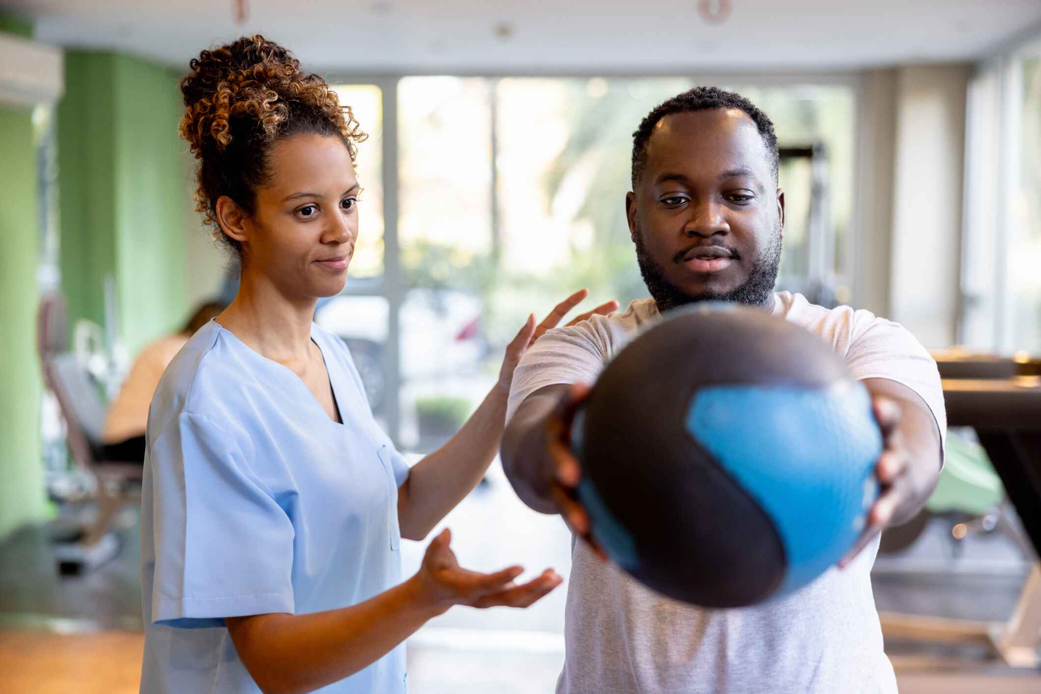 Physical therapist guiding a patient with a medicine ball