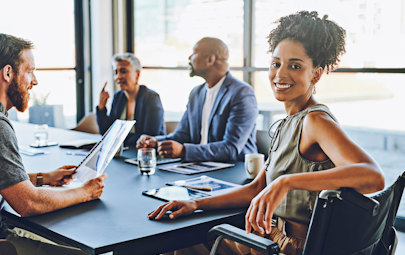 afrian american female locums leadership executive smiles at camera from head of board room table surrounded by team afrian american female locums leadership executive smiles at camera from head of board room table surrounded by team