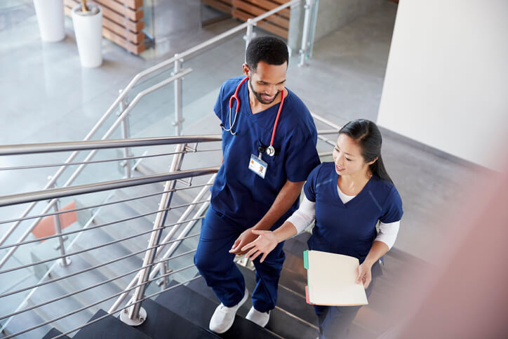 male and female healthcare professionals talking while climbing hospital stairs
