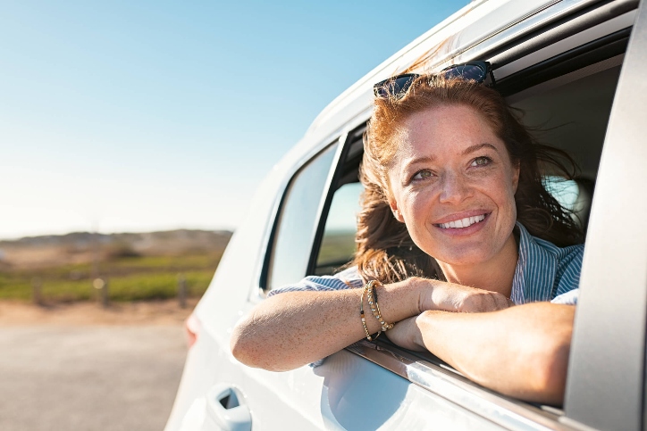 Woman smiling with her head outside the window of a car Woman smiling with her head outside the window of a car