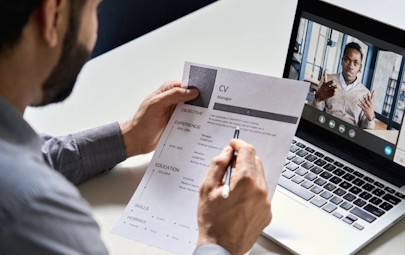 Male healthcare recruiter reviewing a resume at a desk during a video conference call Male healthcare recruiter reviewing a resume at a desk during a video conference call