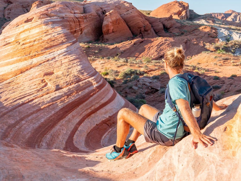 Male hiker sitting on the mountain wearing a backpack. 