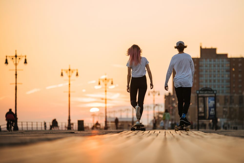 Two individuals skateboarding down the street