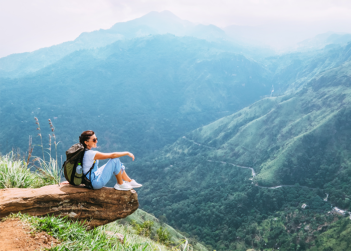Woman sitting on rock overlooking mountains and a valley