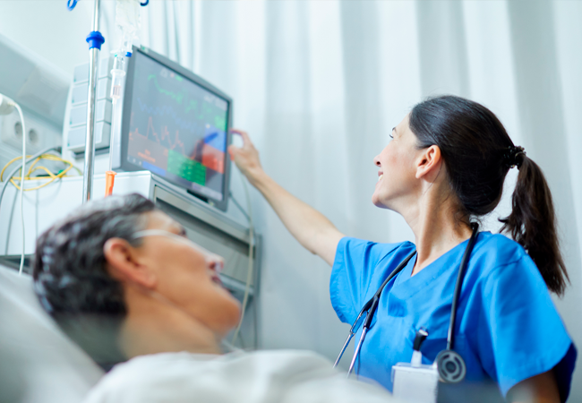Female nurse checking vitals by patient's bedside